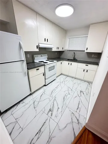 a kitchen with granite countertop white cabinets and white appliances