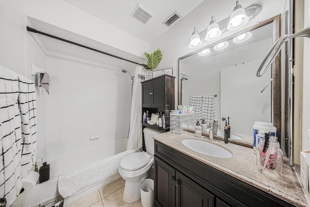 3408 Timberwood Circle, Unit 1360 Naples, FL 34105 - Photo 18 of 36 a bathroom with a granite countertop sink a toilet a mirror a vanity and shower
