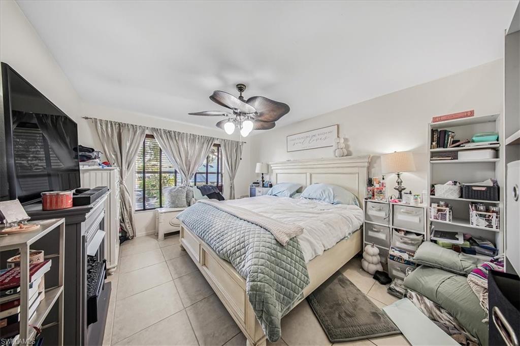 3408 Timberwood Circle, Unit 1360 Naples, FL 34105 - Photo 23 of 36 a spacious bedroom with a large bed and a book shelf