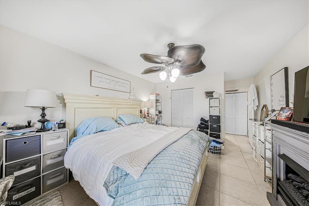 3408 Timberwood Circle, Unit 1360 Naples, FL 34105 - Photo 26 of 36 a bedroom with a bed and a chandelier