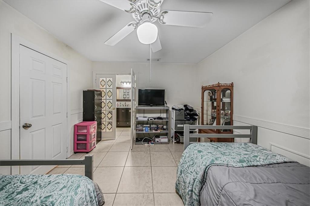 3408 Timberwood Circle, Unit 1360 Naples, FL 34105 - Photo 32 of 36 a bedroom with a bed a flat screen tv and chandelier