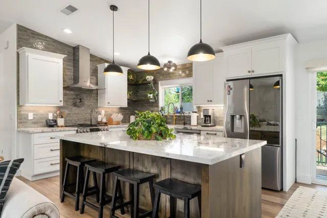 a kitchen with stainless steel appliances kitchen island granite countertop a table chairs and white cabinets