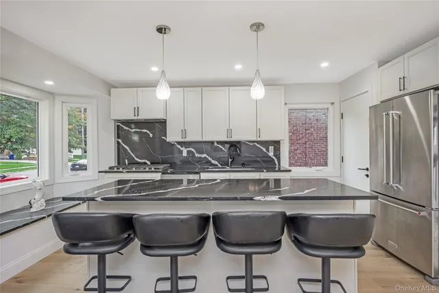 a kitchen with stainless steel appliances granite countertop a sink a stove a kitchen island with chairs and cabinets