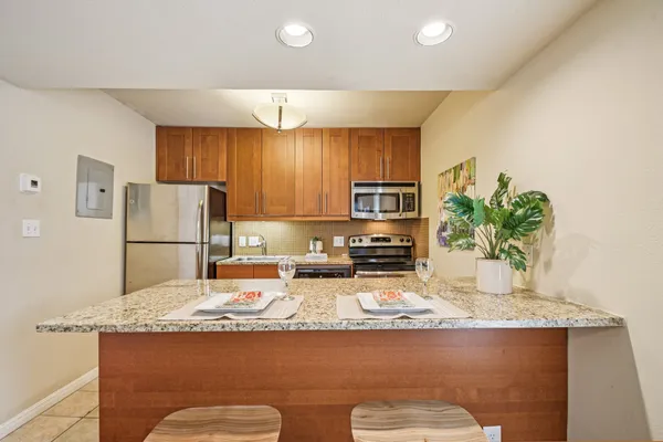 a kitchen with granite countertop a sink a stove a refrigerator cabinets and wooden floor
