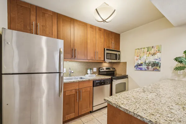 a white refrigerator freezer sitting in a kitchen with stainless steel appliances granite countertop cabinets and a refrigerator