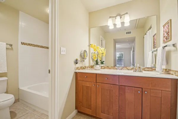 a bathroom with a double vanity sink toilet mirror and bathtub