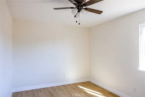 an empty room with a window and a fan