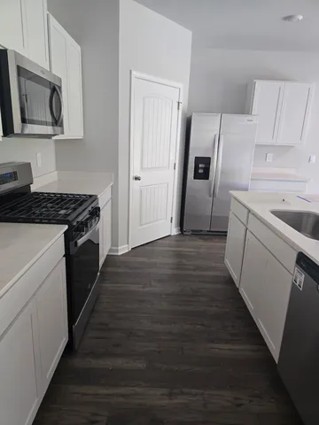 a kitchen with granite countertop a refrigerator and a stove top oven