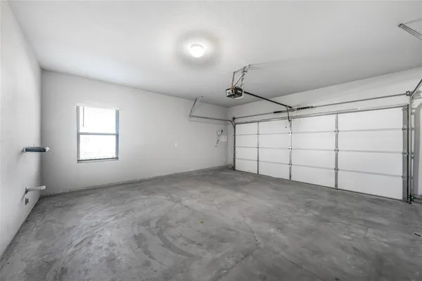 an empty room with chandelier fan and windows