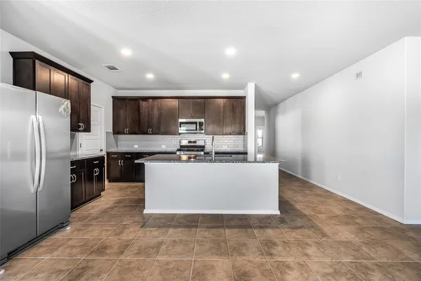 a large kitchen with a refrigerator a stove top oven and a sink