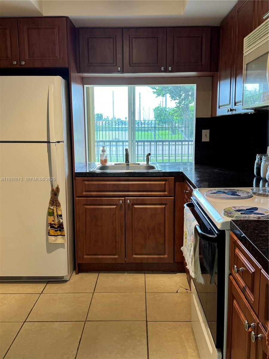 9411 Southwest 4th Street, Unit 111 Miami, FL 33174 - Photo 23 of 28 a kitchen with a cabinets and a stove top oven