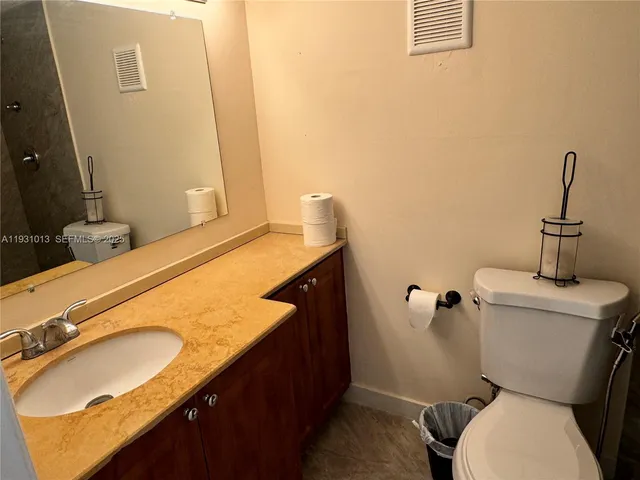 a bathroom with a granite countertop toilet sink and mirror