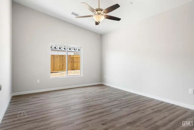 a view of an empty room with window and wooden floor