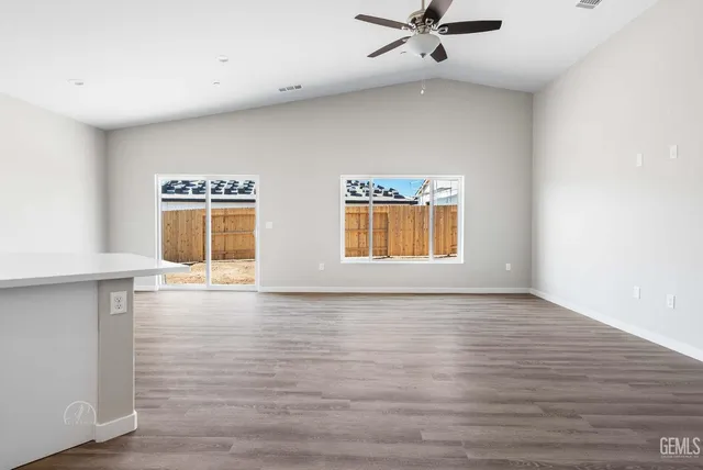 a view of an empty room with window and wooden floor