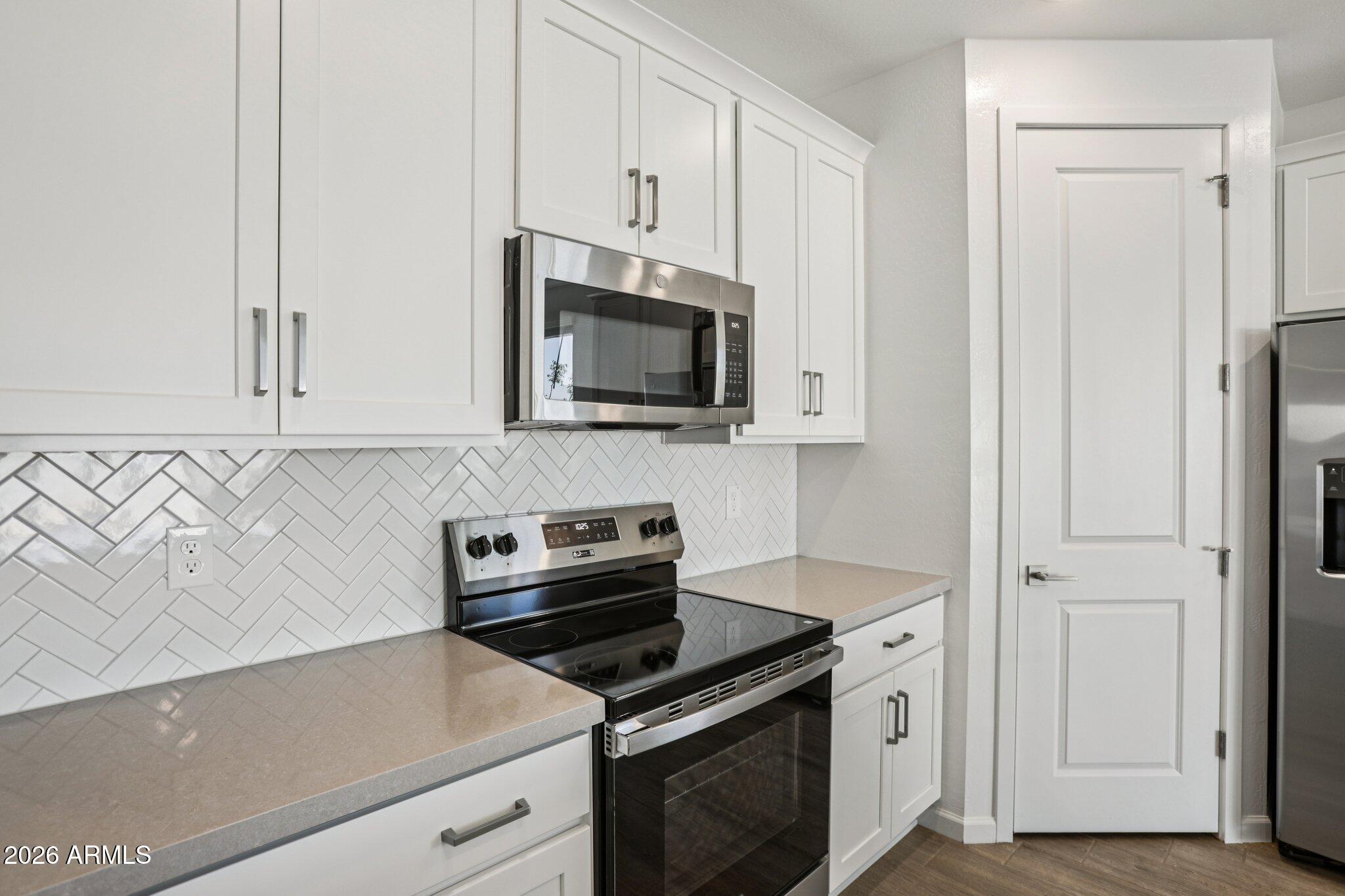 32094 Buckaroo Road San Tan Valley, AZ 85140 - Photo 11 of 46 a kitchen with stainless steel appliances granite countertop white cabinets a stove top oven