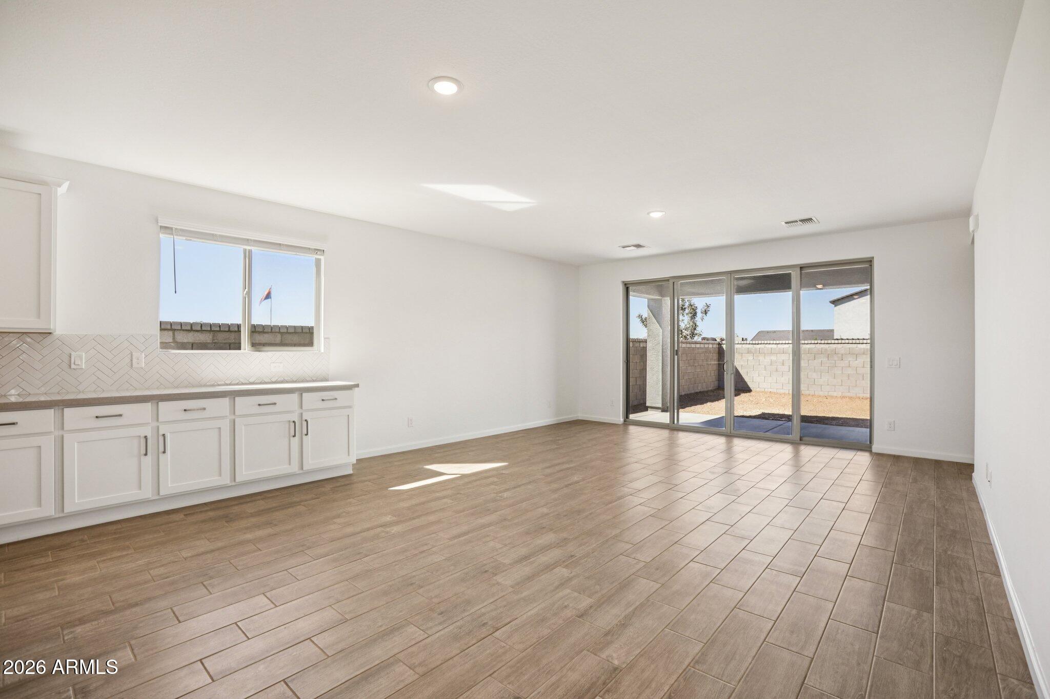 32094 Buckaroo Road San Tan Valley, AZ 85140 - Photo 7 of 46 a large white kitchen with wooden floors and white walls