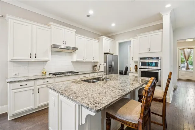 a kitchen with stainless steel appliances granite countertop a kitchen island a stove a table and chairs