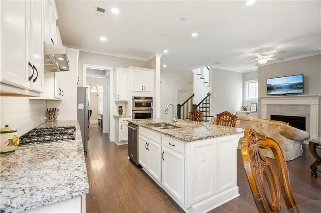 a open kitchen with stainless steel appliances granite countertop a stove oven and a refrigerator with white cabinets
