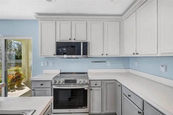 a kitchen with granite countertop a stove a sink and a white cabinets