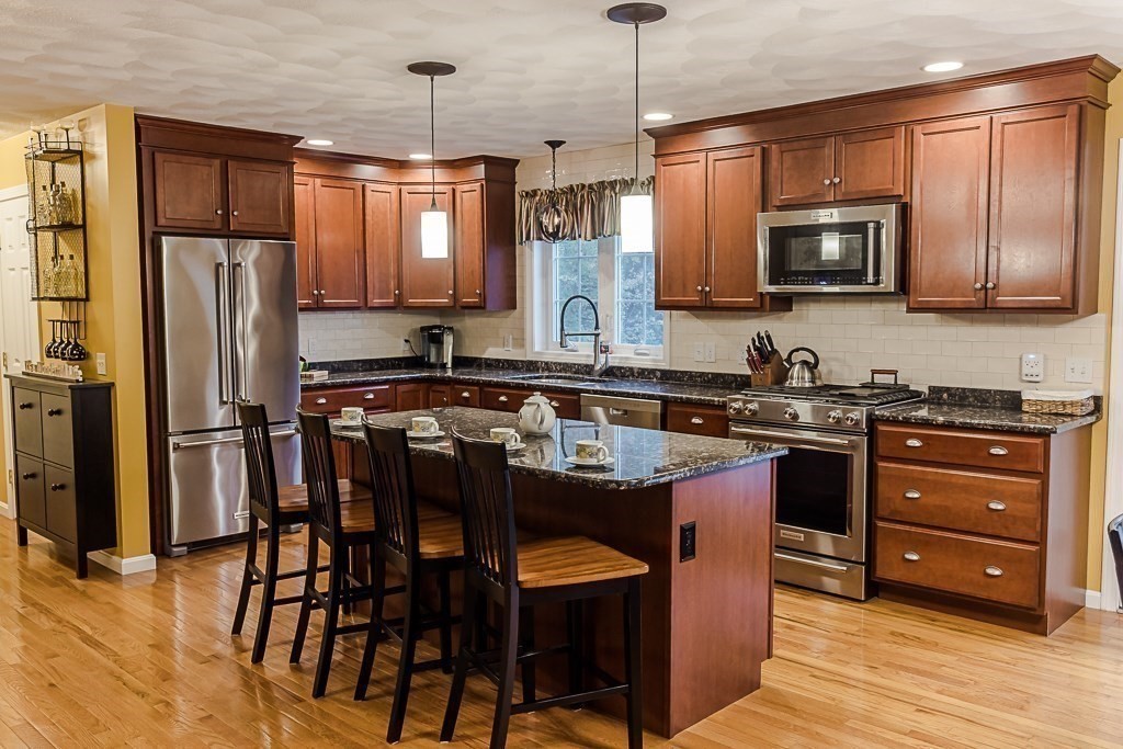77 Baker Road Salisbury, MA 01952 - Photo 13 of 42 a kitchen with stainless steel appliances granite countertop a refrigerator a stove a sink a dining table and chairs with wooden floor