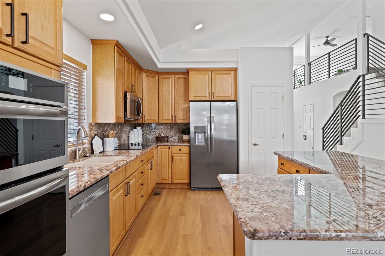 9838 Cypress Point Circle Lone Tree, CO 80124 - Photo 19 of 50 a kitchen with stainless steel appliances granite countertop a refrigerator a stove and a sink with wooden floor