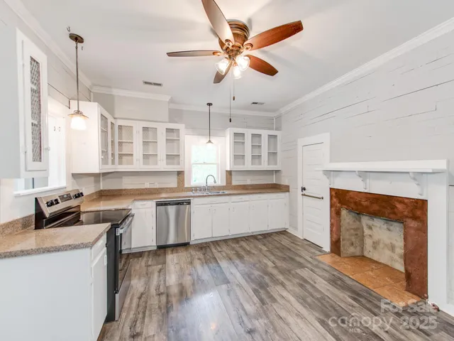 a kitchen with stainless steel appliances granite countertop a stove a sink dishwasher and a fireplace with wooden floor