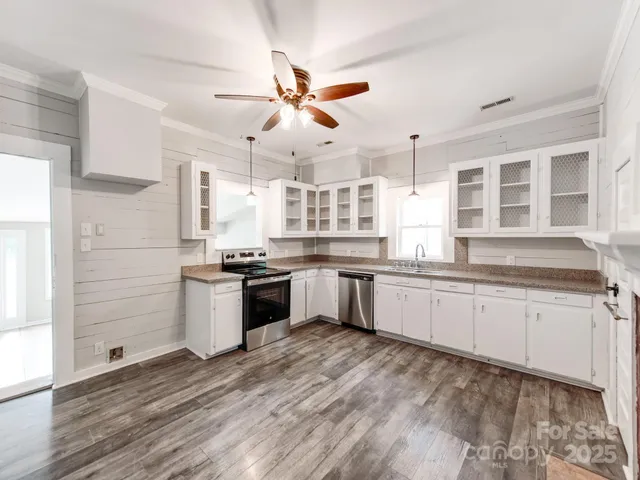 a large kitchen with granite countertop a large counter top space appliances and cabinets