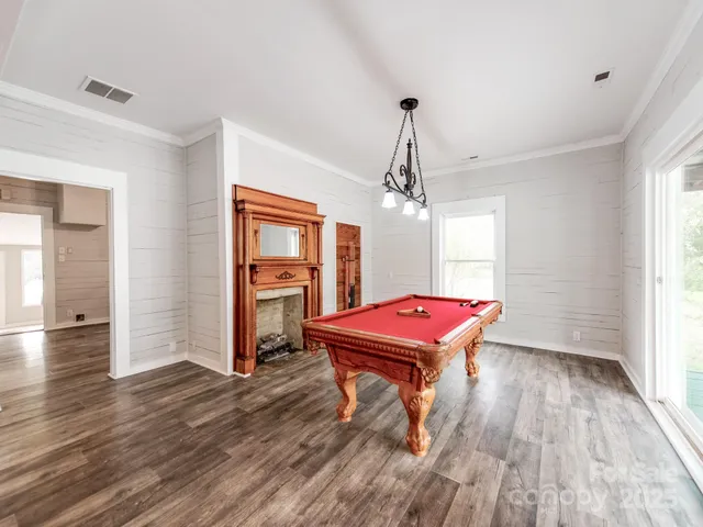 a room with pool table wooden floor and chandelier