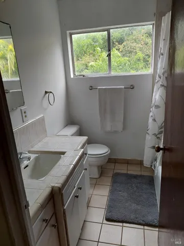 a bathroom with a granite countertop sink toilet and a window