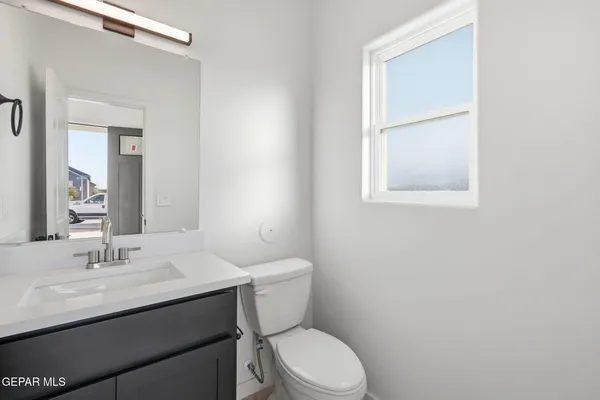 a bathroom with a toilet a sink a mirror and a window