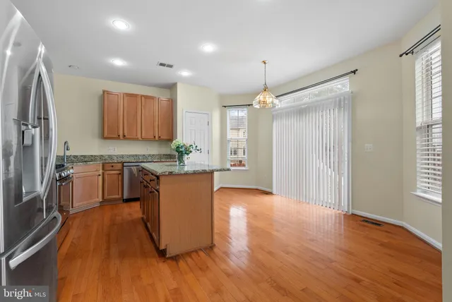 a large kitchen with a center island wooden floor stainless steel appliances and windows