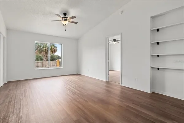 an empty room with wooden floor chandelier and windows