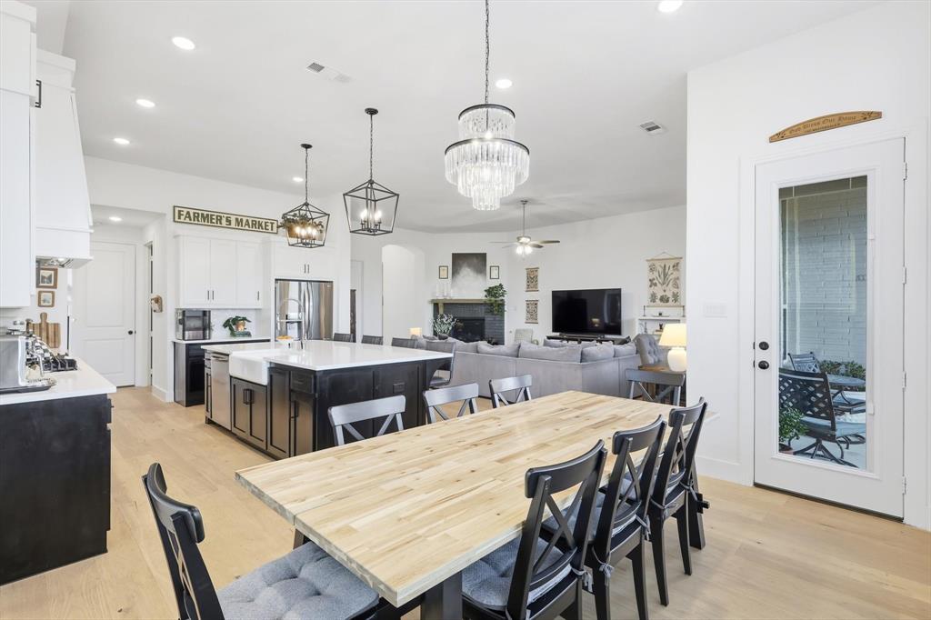 4608 Mount Vista Road Oak Point, TX 75068 - Photo 23 of 39 Open-concept living area featuring light wood-finish flooring, a kitchen island with a farmhouse sink, stainless steel appliances, and a chandelier