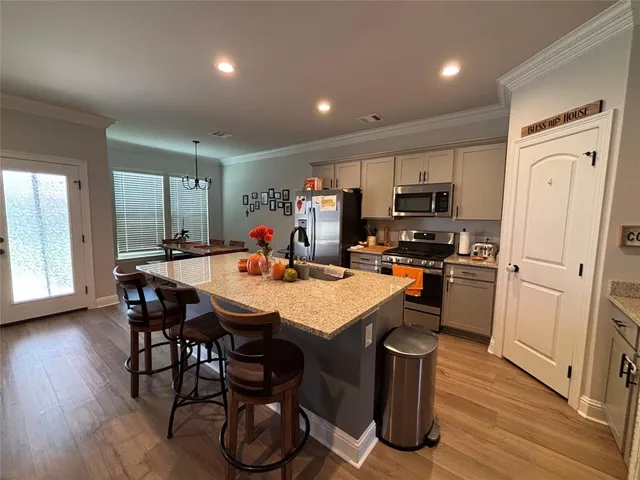a kitchen with stainless steel appliances granite countertop a table chairs refrigerator and sink
