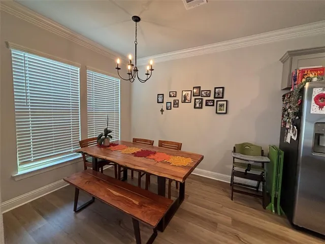 a dining room with wooden floor a chandelier a wooden table and chairs