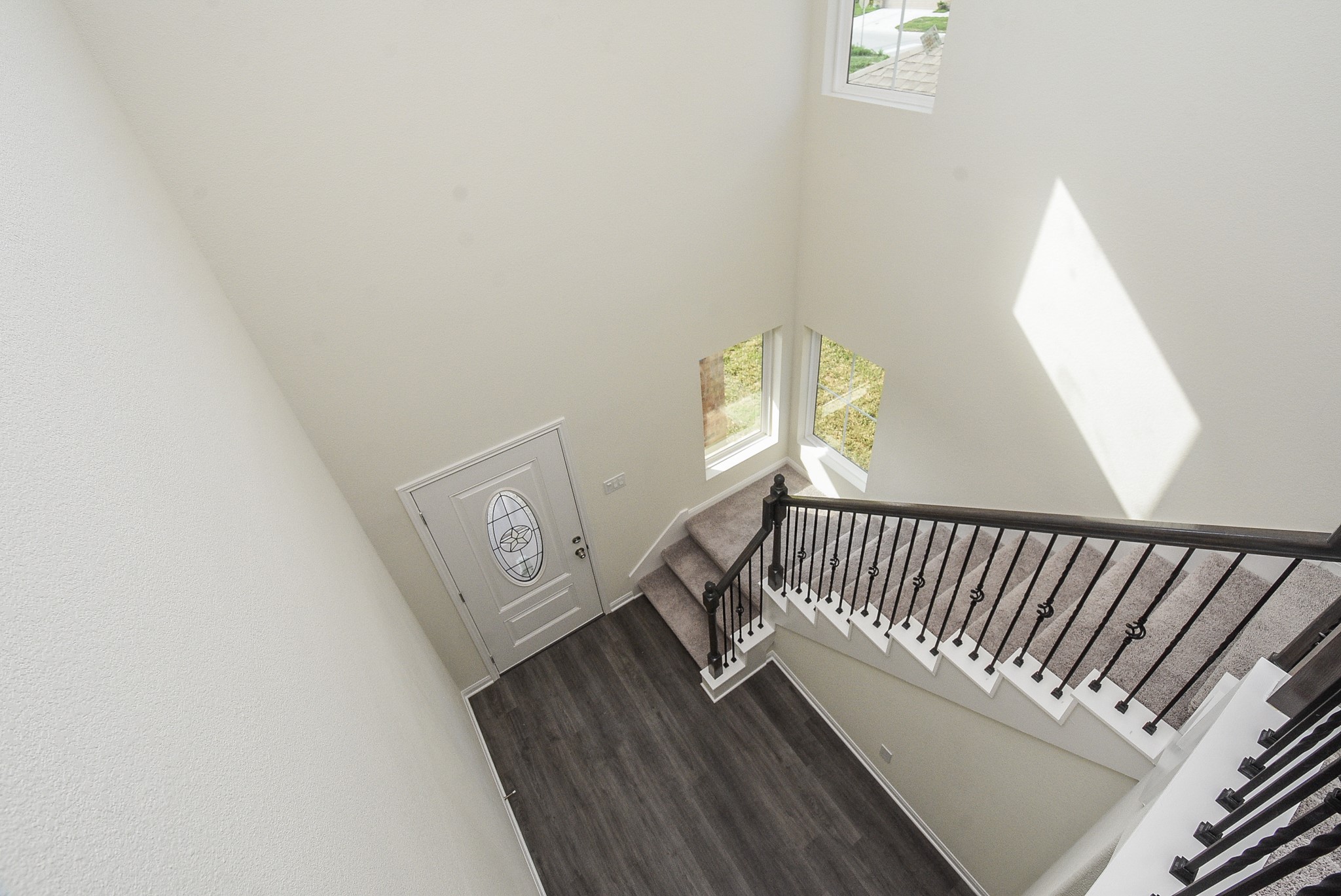 2811 Topiary Lane Houston, TX 77014 - Photo 25 of 32 High-angle view of a modern stairway with dark wooden flooring, white walls, natural light, and an ornate metal balustrade.