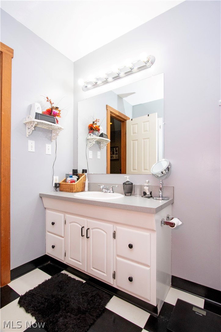 1043 North Honeytown Road Wooster, OH 44691 - Photo 18 of 46 Bathroom vanity with light grey countertop, white cabinetry with black hardware, and an integrated white sink with a chrome faucet