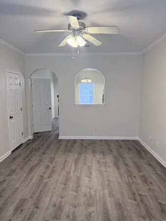 an empty room with wooden floor chandelier fan and windows