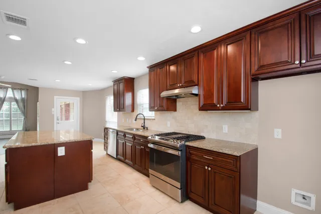 a kitchen with stainless steel appliances granite countertop wooden cabinets a stove top oven a sink and dishwasher