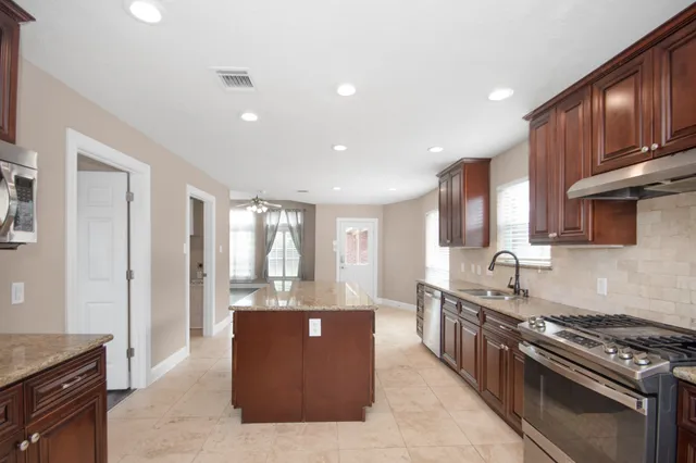 a large kitchen with stainless steel appliances granite countertop a stove and a sink