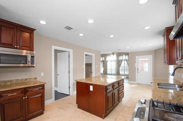 a large kitchen with stainless steel appliances granite countertop a stove a sink and a microwave