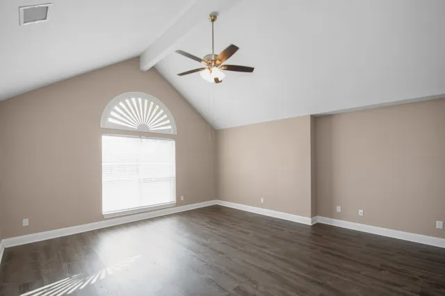 an empty room with wooden floor chandelier fan and windows