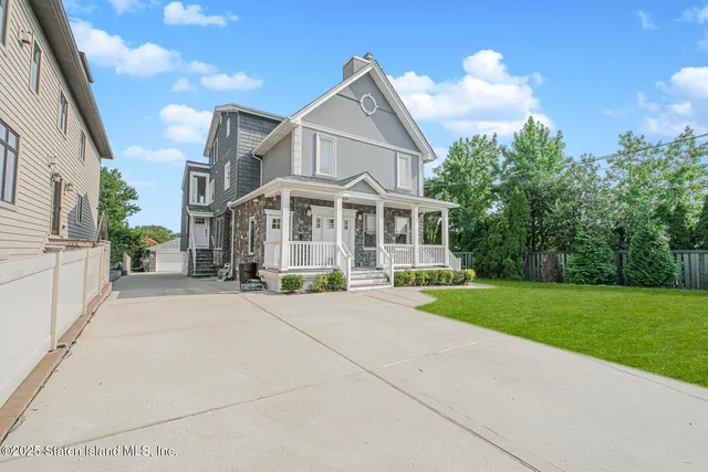 a view of a white house with a yard and potted plants