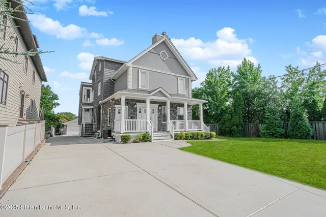 a view of a white house with a yard and sitting area