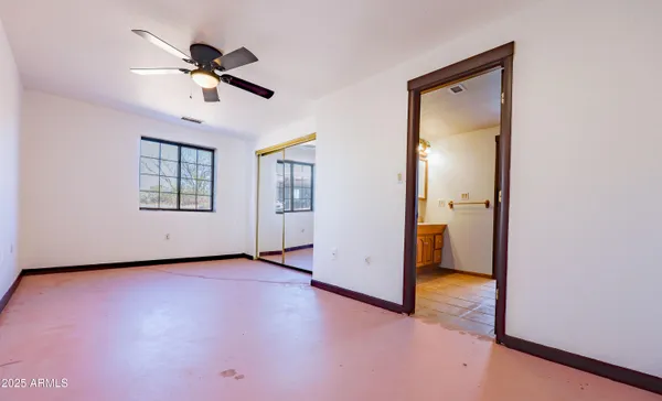 an empty room with windows and a ceiling fan