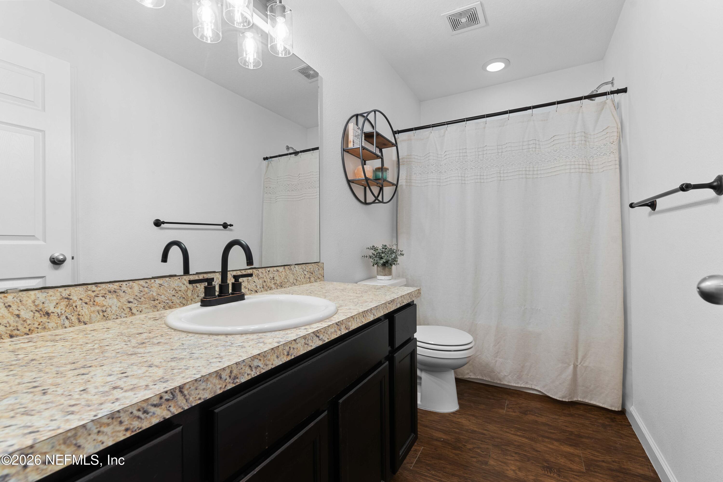 6178 Daylilly Road Macclenny, FL 32063 - Photo 20 of 29 a bathroom with a granite countertop sink a toilet and a mirror