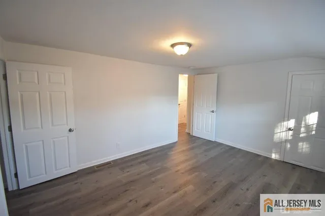 a view of an empty room with wooden floor and windows
