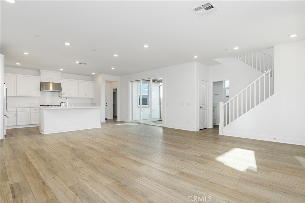 27213 Tamarack Lane Valencia, CA 91381 - Photo 13 of 40 a view of an empty room with wooden floor and a kitchen