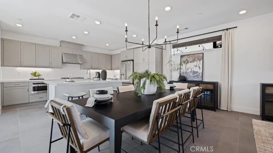 27213 Tamarack Lane Valencia, CA 91381 - Photo 9 of 40 a kitchen with stainless steel appliances kitchen island granite countertop a dining table chairs and white cabinets