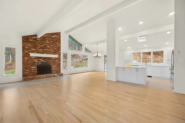 an empty room with wooden floor and a kitchen